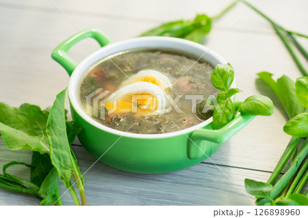 Appetizing spring sorrel borscht isolated on light wooden table Appetizing spring sorrel borscht isolated on light wooden table 126898960
