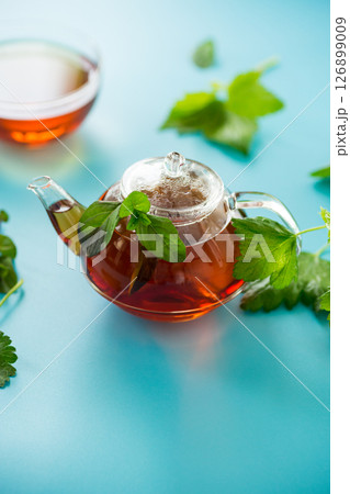 Green tea from currant and mint leaves in a glass teapot 126899009
