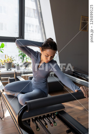 Woman doing mermaid exercise in a sunlite, modern pilates studio, embodying calm, focus, and strength. Woman doing mermaid exercise in a sunlite, modern pilates studio, embodying calm, focus, and strength. 126899125