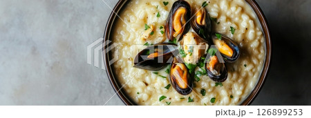 Savor the rich flavors of traditional risotto topped with fresh mussels and parsley, showcasing a warm and inviting meal perfect for any Italian dining experience Savor the rich flavors of traditional risotto topped with fresh mussels and parsley, showcasing a warm and inviting meal perfect for any Italian dining experience 126899253