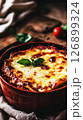 A traditional Italian lasagna is being cooked in a rustic oven, showcasing layers of meat, cheese, and sauce bubbling with flavor, creating an inviting aroma in the kitchen 126899324