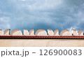 Geometric pattern on top of a light wall against a dark stormy sky 126900083