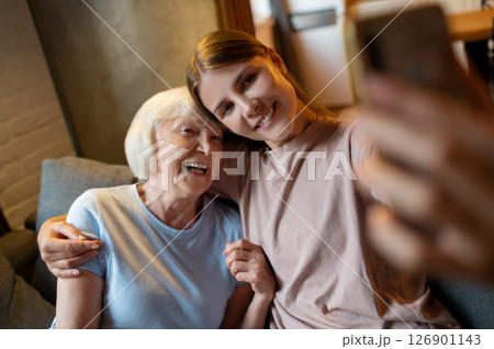 Young female volunteer and elderly woman making selfie and looking enjoyed Young female volunteer and elderly woman making selfie and looking enjoyed 126901143