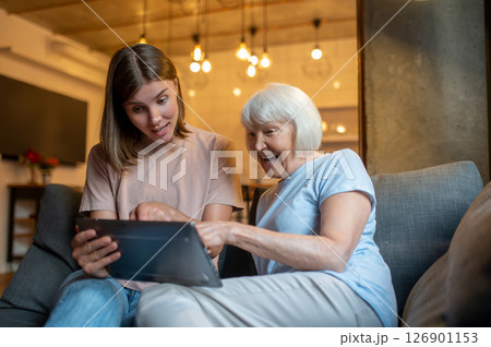 Elderly woman and young volunteer watching something on the laptop together Elderly woman and young volunteer watching something on the laptop together 126901153