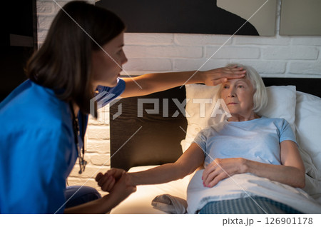 Doctor checking temperature of an elderly woman by touching her forehead 126901178