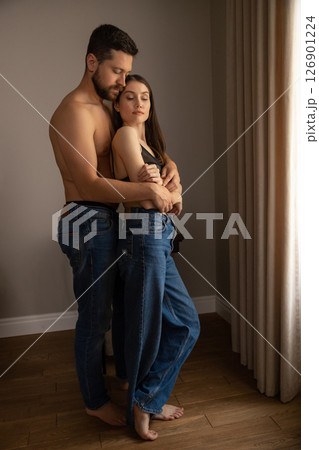 Man in jeans hugging woman their faces close in tender embrace in home setting 126901224