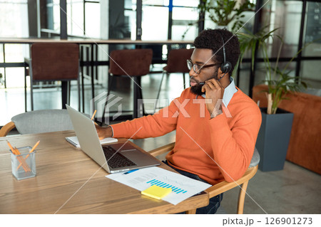 Dark-skinned businessman having a call online and looking involved 126901273