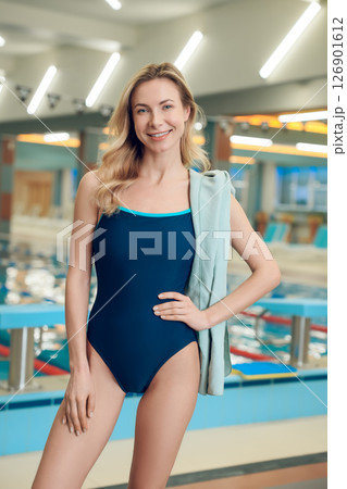 Pretty slim young woman in one-piece swimsuit in the pool looking confident Pretty slim young woman in one-piece swimsuit in the pool looking confident 126901612