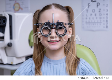 Fair-haired school age girl having an optometry test in clinic 126901658