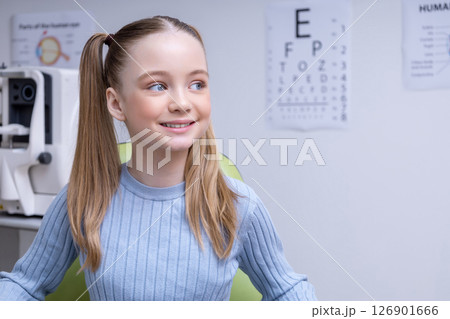 Smiling cute girl sitting in the ophthalmologist office and looking contented 126901666