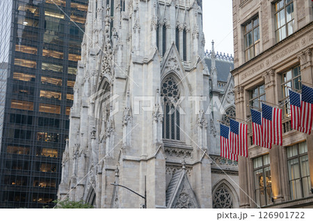 A close-up view of the ornate facade of St. Patrick's Cathedral on 5th Avenue in Manhattan. American flags hang proudly from the building opposite, highlighting New York's patriotic and architectural 126901722