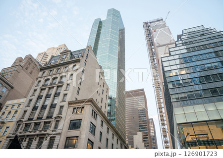 Tall modern skyscrapers with glass facades rise above older, ornate buildings in Midtown Manhattan. The contrast between new architecture and historic design captures the essence of New York's Tall modern skyscrapers with glass facades rise above older, ornate buildings in Midtown Manhattan. The contrast between new architecture and historic design captures the essence of New York's 126901723
