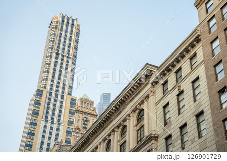 Tall skyscrapers rise behind older, classical buildings in this view of Midtown Manhattan. The contrast between architectural styles highlights New York City's evolving skyline. 126901729