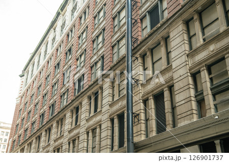 A detailed view of a classic red brick and beige stone building in New York. The architecture features large windows and vintage design. 126901737