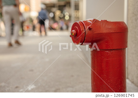 A vibrant fire hydrant is prominently shown with a blurred urban scene behind. The image captures the texture and color of the hydrant in detail. 126901745