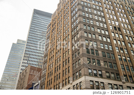 A detailed view of classic office buildings and high-rises in Midtown Manhattan. The photo highlights rows of windows, brickwork, and contrasting modern towers in the background. 126901751