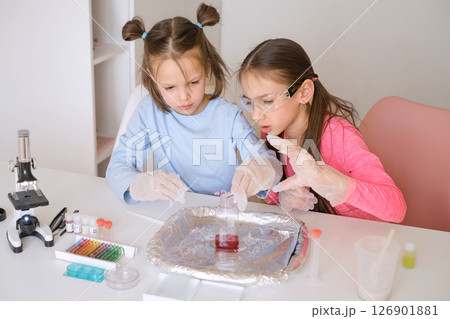 Girls mix liquids in a test tube doing school experiments Girls mix liquids in a test tube doing school experiments 126901881