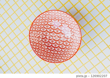 ramen bowl with a pattern stands on a yellow and white checkered table. ramen bowl with a pattern stands on a yellow and white checkered table. 126902207