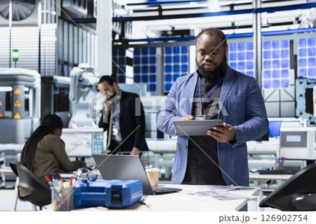 African american supervisor checking solar panel machinery and reviewing a checklist, playing a vital role in renewable energy production and assembly line. Efficient solar tech infrastructure. 126902754