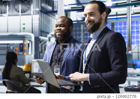 Factory inspectors and supervisors engaging in briefing over production metrics, supporting industrial innovation and sustainable process improvement. Solar power manufacturing. 126902776