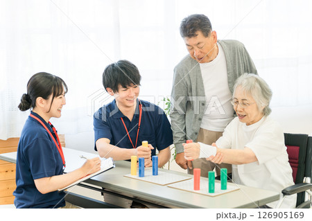 介護施設,リハビリ施設でリハビリするシニア女性,夫婦と作業療法士の男女スタッフ 126905169