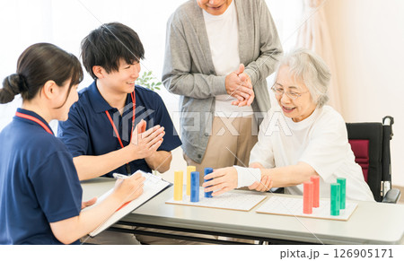 介護施設,リハビリ施設でリハビリするシニア女性,夫婦と作業療法士の男女スタッフ 126905171