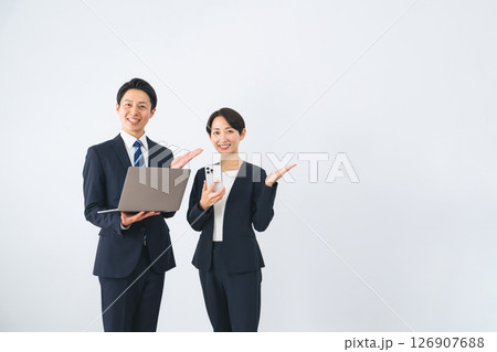 ノートパソコンとスマホを持って案内する男女ビジネスパーソン 126907688