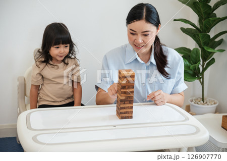 toddler girl with mother playing wooden block toy together toddler girl with mother playing wooden block toy together 126907770