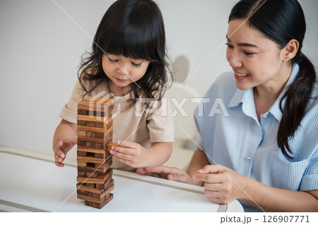 toddler girl with mother playing wooden block toy together toddler girl with mother playing wooden block toy together 126907771
