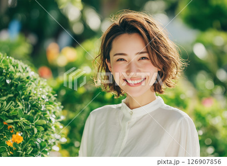 緑に囲まれて笑顔を見せる女性のポートレート写真 126907856