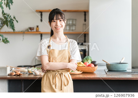 キッチンの前で腕組みするエプロン姿の若いアジア人女性 126907936