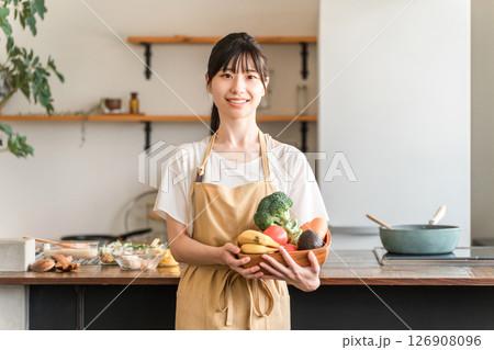 キッチンで野菜を持つエプロン姿のアジア人女性・主婦 キッチンで野菜を持つエプロン姿のアジア人女性・主婦 126908096