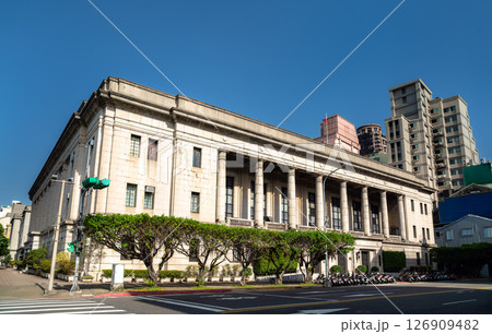 The neoclassical Bank of Taiwan headquarters stands on a sunny street corner in Taipei's Zhongzheng District, its tall granite colonnade and symmetrical stone facade contrasting with nearby modern The neoclassical Bank of Taiwan headquarters stands on a sunny street corner in Taipei's Zhongzheng District, its tall granite colonnade and symmetrical stone facade contrasting with nearby modern 126909482