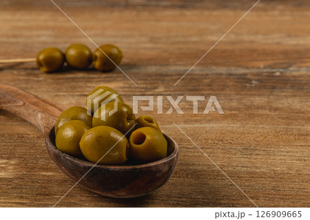 Delicious green olives in a wooden spoon on rustic table Delicious green olives in a wooden spoon on rustic table 126909665
