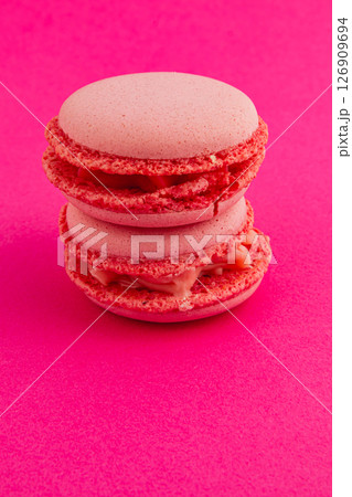 Colorful macarons stacked on pink background for dessert display 126909694