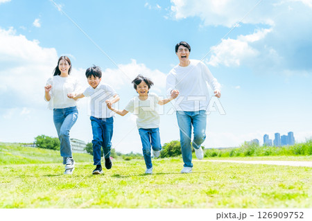 青空の草原を走る家族 126909752