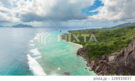 Aerial view of clear turquoise waters and granite rocks along a tropical beach with lush vegetation. La Digue, Seychelles. 126910037