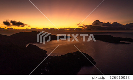 A fiery sunset bathes the horizon in warm light, while the islands and water rest in shadows. Praslin, Seychelles. A fiery sunset bathes the horizon in warm light, while the islands and water rest in shadows. Praslin, Seychelles. 126910038