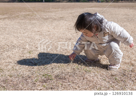 【相模原市立麻溝公園の芝生広場で遊ぶ1歳児　しゃがむ】 126910138