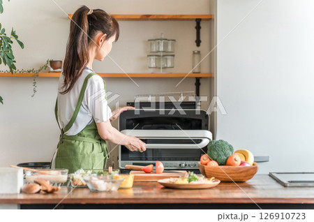 キッチンで電子レンジを使う女性（料理代行,家事代行,家政婦,ヘルパー） 126910723