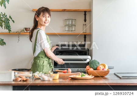 キッチンで電子レンジを使う女性(笑顔) キッチンで電子レンジを使う女性(笑顔) 126910724