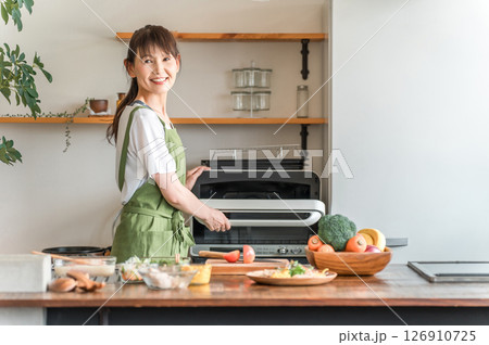 キッチンで電子レンジを使う女性（笑顔） 126910725