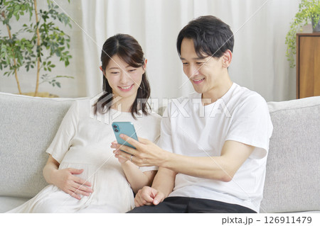 リビングでスマホを使う妊娠中の妻と夫 126911479