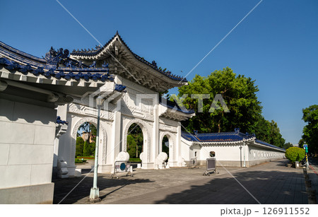 Crisp morning view in Taipei, Taiwan, shows a triple-arched white gate with deep-blue tiled roofs and dragon ornaments marking a side entrance to Liberty Square at Chiang Kai Shek Memorial Hall 126911552