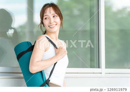 ヨガマットを持った健康的な女性(ヨガ講師・ヨギーニ) ヨガマットを持った健康的な女性(ヨガ講師・ヨギーニ) 126911979