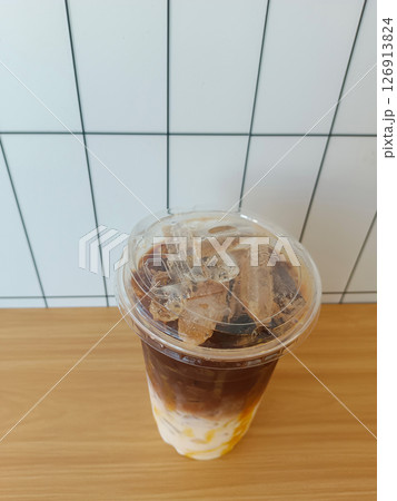 top view caramel coffee in a plastic cup, placed on a table, white tile wall background, drink, food, fashion, copy space 126913824
