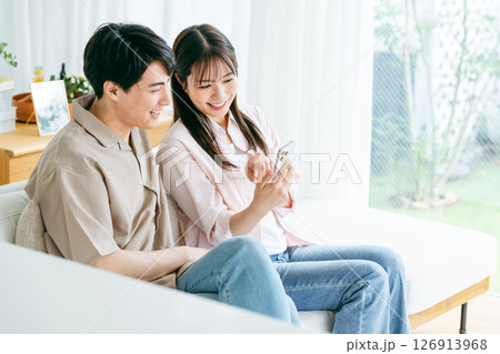 リビングでスマホを見るカップル リビングでスマホを見るカップル 126913968