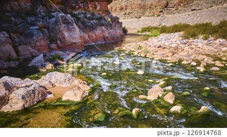 Aerial Virgin River Motion Over Mossy Rocks and Red Canyon Walls 126914768