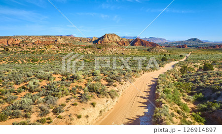 Aerial Fly Through Red Rock Formations Sagebrush Plain and Winding Dirt Road 126914897