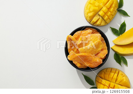 A bowl of dried mango chips with fresh sliced mango 126915508